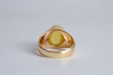 Gold ring with a yellow gemstone on a light gray background
