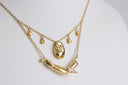 Gold necklace with pendant on a light gray background