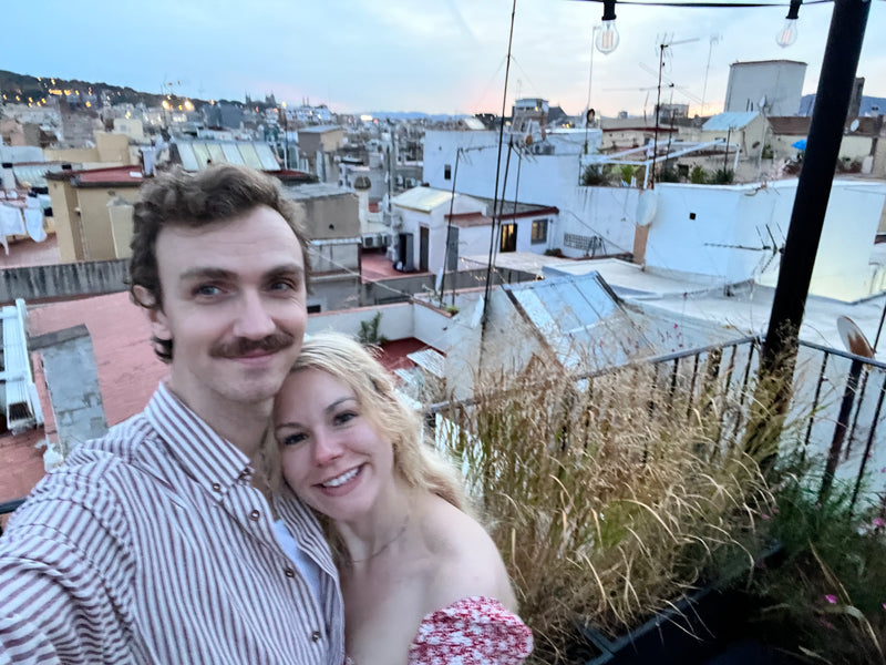 Two people on a rooftop with cityscape in the background