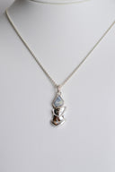 Silver necklace with a face-shaped pendant on a mannequin against a white background