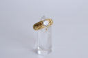 Gold ring with a diamond on a clear crystal stand against a light gray background
