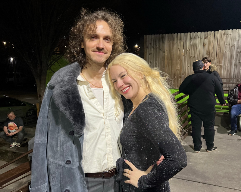 Two people posing together outdoors at night.