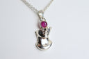 Silver pendant with a red gemstone on a white background