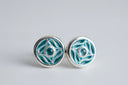 Pair of silver earrings with blue enameled design on a light gray background