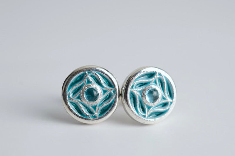 Pair of silver earrings with blue enameled design on a light gray background