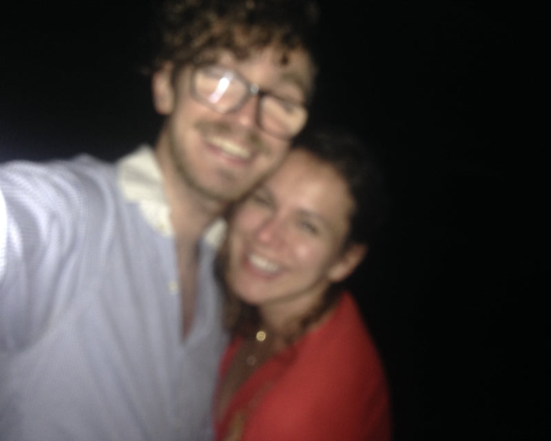Two people smiling at the camera with a dark background
