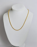 Gold chain necklace on a white mannequin bust against a plain background
