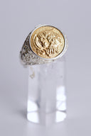 Gold and silver ring on a clear stand against a light gray background