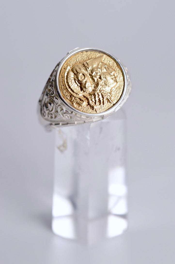 Gold and silver ring on a clear stand against a light gray background