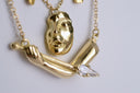 Gold necklace with a unique pendant design on a light gray background
