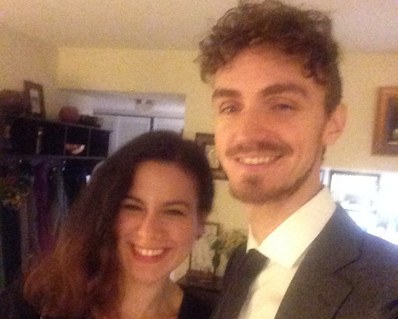 Two people smiling at the camera in a room with decor and equipment.