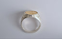 Silver ring with intricate design on a gray background