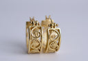 Gold hoop earrings with intricate designs on a light gray background