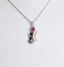 Silver necklace with a heart-shaped pendant and red gemstone on a white background