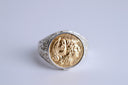 Silver ring with a gold coin embedded on a light gray background