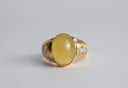 Gold ring with a yellow gemstone on a gray background
