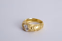 Gold ring with a clear gemstone on a light gray background
