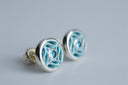 Silver earrings with intricate design on a light gray background