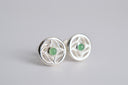 Silver earrings with green gemstones on a light gray background