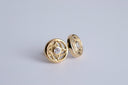 Gold earrings with intricate design on a light gray background