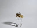 Gold ring on a clear crystal stand against a gray background