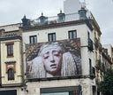 Building facade with a large mural of a face on the side